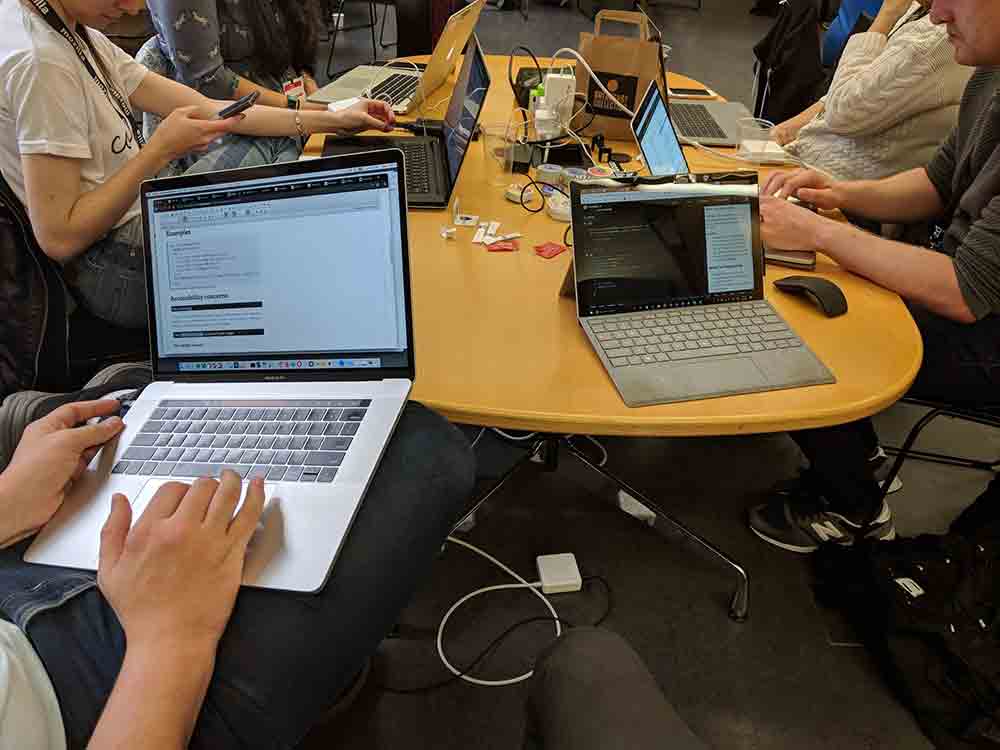A bunch of laptops on a table surrounded by worker drones.